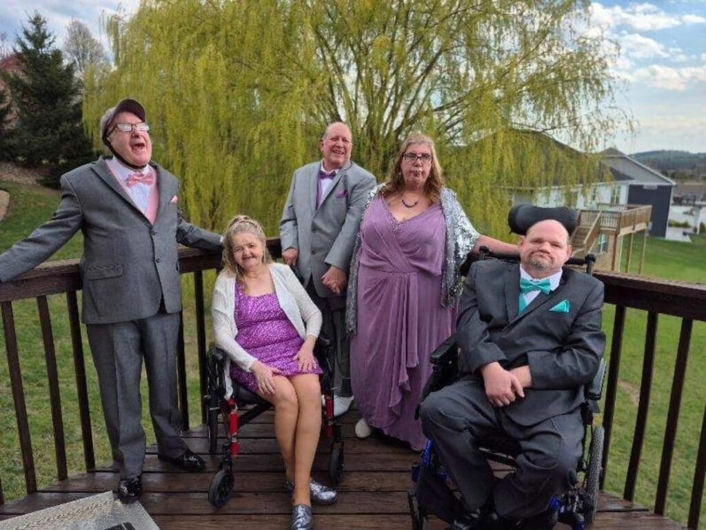 five friends are dressed up for a dance and posing together on their back deck.