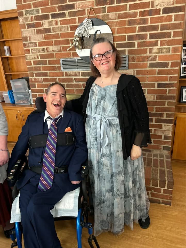 Two adults are dressed up for a dance and smiling.