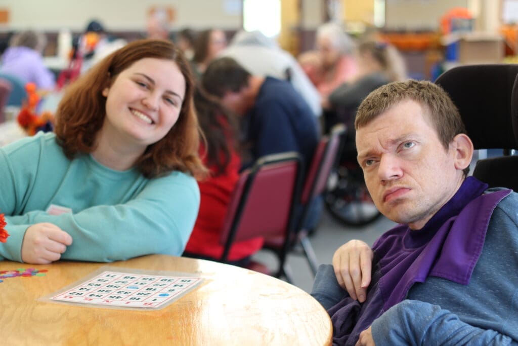 Two people sitting at a table with a bingo card in front of them