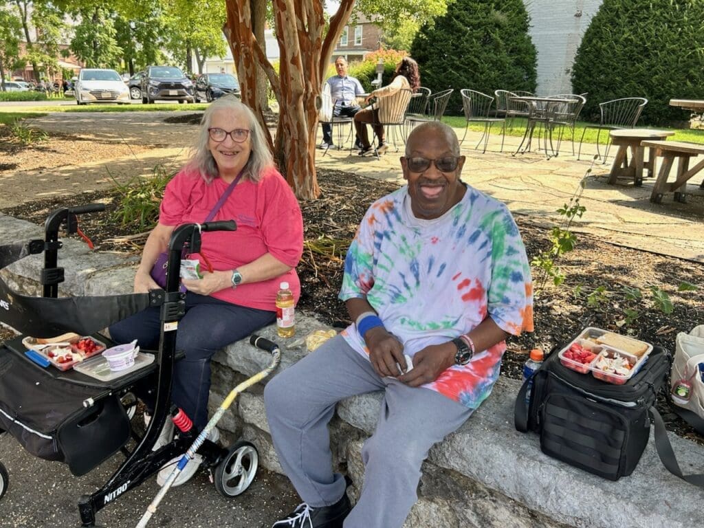 Two people sitting under a tree and smiling